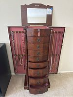 Front view of opened jewelry box showing drawers and side wings with necklaces hooks.