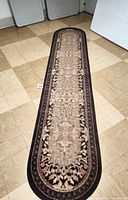 Full view of the brown carpet runner on floor showing entire length with floral patterns and rounded edges.