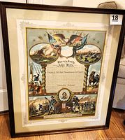 Full-view of framed certificate leaning against chair on hardwood floor showing Lot 18 sticker