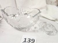 Both crystal bowls shown together on white cloth background, large scalloped bowl with floral cut and etched details alongside smaller kidney-shaped etched bowl
