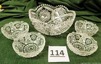 Photo showing 4 small leaded crystal bowls arranged around a larger bowl with scalloped edges and detailed cut star patterns.