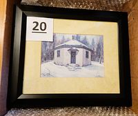 Framed print of the octagonal Diamond Rock Schoolhouse in winter with a black frame and beige mat, showing some wear on back of frame.