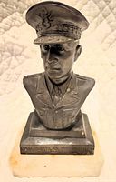 Front and slightly angled views of the metal bust statue of Gen. Douglas McArthur mounted on a marble base showing inscription and condition.