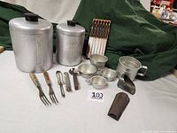 Full lot view showing all kitchenware items including canisters, forks, tin measuring cups, and cutlery set