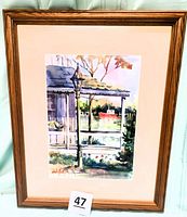 Framed watercolor painting showing a porch with a lamp post and a red boat on water in the background. Contains artist signature and a lot number card 47.