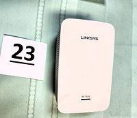 Front view of white compact Linksys RE7000 WiFi extender with model number visible, showing clean condition and device design.