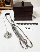 Photo showing the stacked wooden jewelry box with three trays, 3-strand glass bead necklace, silver chain necklace with abalone and pearl pendant, and linked bracelet.