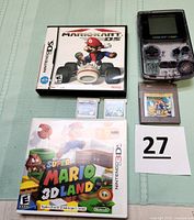 Nintendo Game Boy Color handheld console transparent purple with five game cartridges: original Game Boy Super Mario Land, two Nintendo DS carts including Mario Kart DS, two Nintendo 3DS carts including Super Mario 3D Land in box.