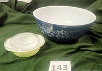 Photo of both the large blue floral Pyrex mixing bowl and small lime green casserole dish with clear lid on a green fabric background.