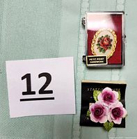 Red rose petit point handwork in an oval pendant within a clear display case, placed along with the Staffordshire China floral pin on original backing paper.