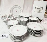 Complete set of Royal Swirl fine china including plates, bowls, cups, saucers and boxed Reze tablecloth shown arranged on white backdrop.