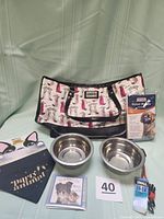 Full lot contents including Lulu Guinness tote bag with Scottie dog print, two metal dog bowls, small dog collar, dog bandana, and nylon muzzle in packaging.