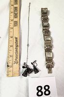 Full view of the bracelet, necklace with bell pendant, and matching earrings with a ruler for size reference