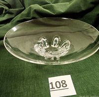 Front angled view showing overall shape and horseshoe-footed base of clear crystal bowl against green fabric background.