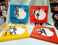 Four colorful box sets standing and laying on a light green fabric surface, showing front cover artwork and titles The Swing Era series from Time Life Records