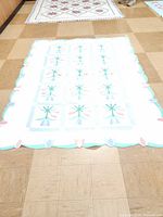 Full view of vintage Arch Quilt on tiled floor showing overall size and scalloped edges with tulip motifs