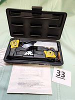 Photo showing the open case containing the Versa Cut cutting tool, two yellow circular blades attached on either side, additional metal blades, and an instruction sheet underneath.