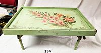 Green wooden breakfast tray with foldable legs extended, showing hand-painted floral design on the tray surface.