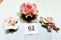 Front view of three porcelain roses, pink candle holder in center, white rose left, dusty pink rose right.