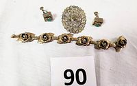 Full set of jewelry items displayed together: brooch, bracelet, earrings
