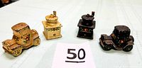 Four miniature cast iron salt and pepper shakers: two in the shape of antique Model A cars and two in the shape of coffee grinders, all with floral hand-painted details and intact cork stoppers.