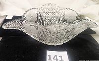 Side view of the oval cut lead crystal bowl showcasing the scalloped sawtooth rim, etched flowers, and diamond cut detail along with unique handles.