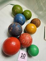 Set of eight vintage wooden bocci balls in assorted colors showing wear and age-related paint chipping.