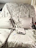 Full view of the Waterford Blenheim comforter draped showing the damask print and coordinating pillows and shams arranged in front.