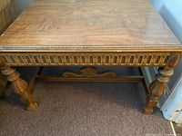 Top and side view showing carved frieze with repeating motifs and wood grain on table surface