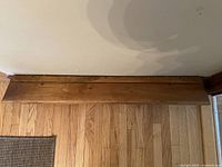 Top view of the antique wooden plate display shelf showing smooth stained wood surface and ledge for holding plates.