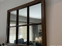 Front view of the wall-mounted mirror showing six panels divided by wooden muntins and reflections of interior room.