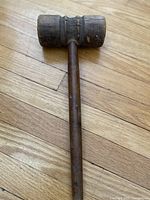 Photo showing wooden mallet head and handle on wooden floor, displaying overall condition and shape.