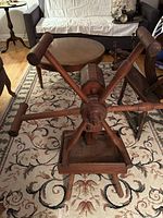 Front view of antique wooden spinning wheel on tripod base, showing pegs and hexagonal frame.