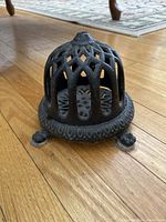 Side angle view of antique cast iron yarn dispenser showing lattice dome and decorative base with feet.