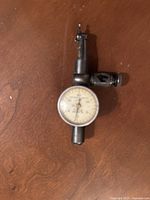 Starrett 711LCSZ dial test indicator with circular dial and probe, shown on wooden surface.