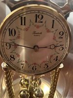 Close-up of clock face showing decorative floral elements, black Arabic numerals, and clock hands