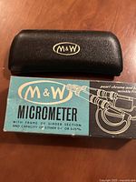 Original black protective case with M&W logo and original blue and black box with branding and product illustration.