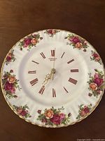 Front view of the Royal Albert Old Country Roses clock showing floral pattern and Roman numerals