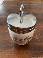 Front view of the Royal Worcester porcelain egg coddler showing pink floral pattern and metal lid with loop handle.