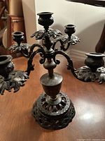 Close-up side angle showing ornate details of the cast iron candelabra and one candle holder.