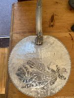 Top view showing hammered texture, floral embossed design on lid, and decorative handle with flower motif