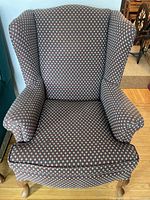 Front view of the wingback chair showing overall condition and upholstery pattern.