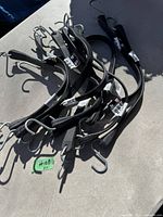 Eleven black rubber tarp straps with metal hooks on each end spread on a surface with a green tag indicating quantity of 11.
