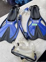 Photo of snorkeling fins, snorkel, and mask laid out on a surface, showing brand and condition.