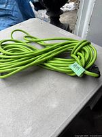 Bright green 50-foot extension cord coiled on a flat surface showing plug end with no visible damage.