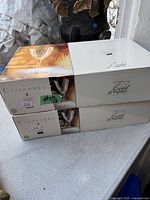 Two unopened white boxes labeled Cassandra containing four crystal wine glasses each, with the brand Cristal d'Arques visible on the box.