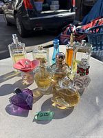 Photo of 10 assorted ladies perfume bottles placed outside on a table, showing various bottle shapes, colors, and caps.
