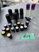 Photo depicting a variety of essential oil bottles arranged on a table, including both larger and smaller bottles, some with colored labels and some clear glass roller bottles.