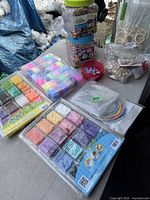 Wide view of multiple bead kits sealed in plastic trays featuring pastel and bright colored beads in separate compartments along with small bead containers and bead frames.