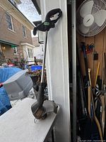 Side view of the full weed eater showing the handle, shaft, and cutting head with guard.